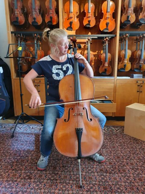 Eine Frau mit Brille spielt Cello in einem Geschäft für Streichinstrumente.